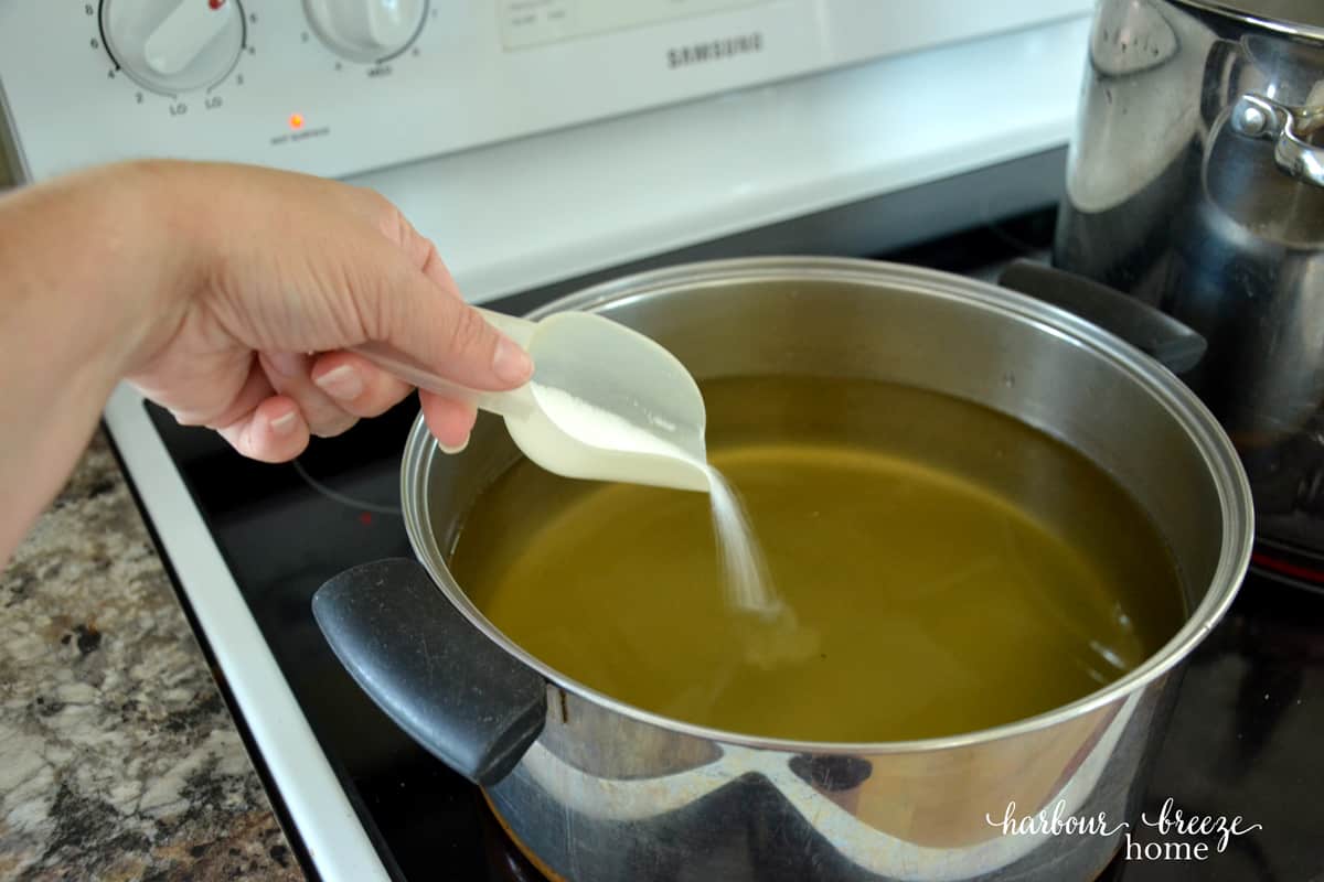 Sugar being added to a pot of apple juice.