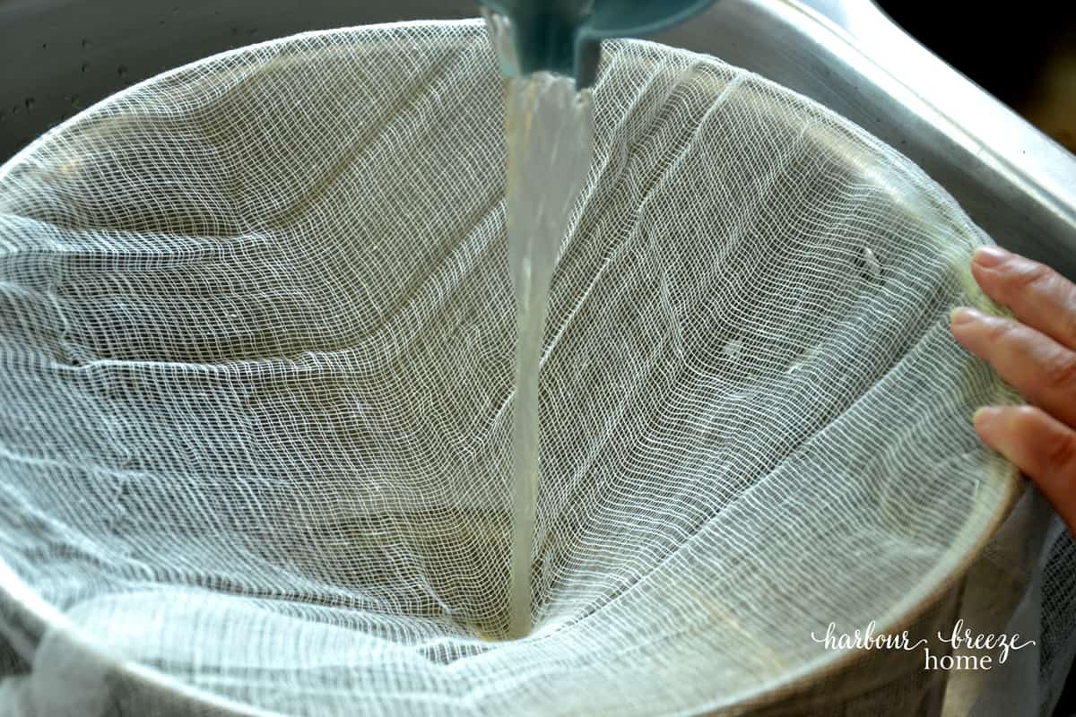 Apple juice being strained using cheesecloth