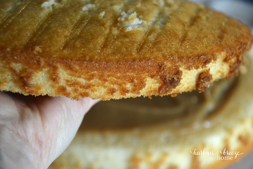 The second layer cake being placed on the first layer with the flat side down.