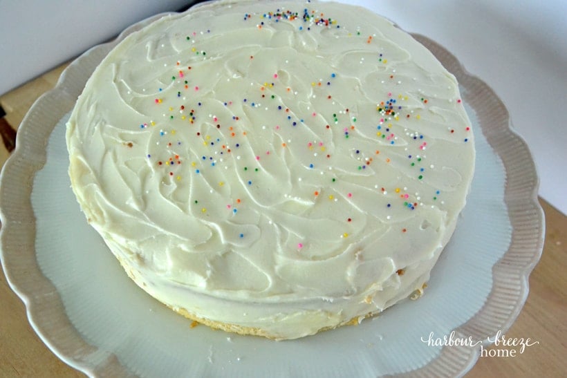 The top of a finished stacked cake with frosting and sprinkles on it.