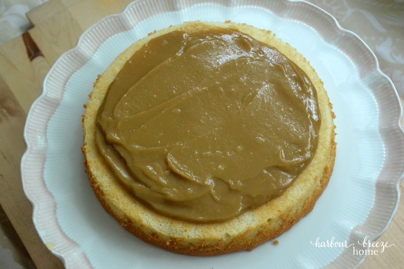 The bottom layer of a stacked cake with butterscotch filling on it.