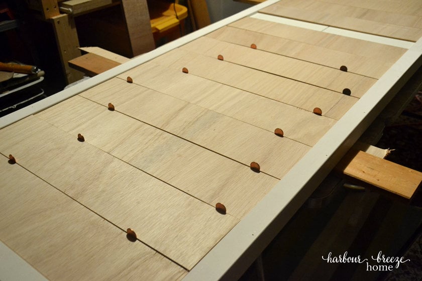 The front of a bi-fold closet door that has been modified with strips of wood to look like shiplap.