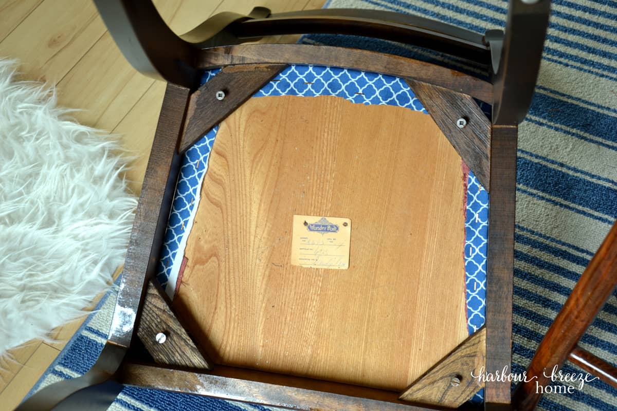 The underside of a dining chair with the cushion screwed on.