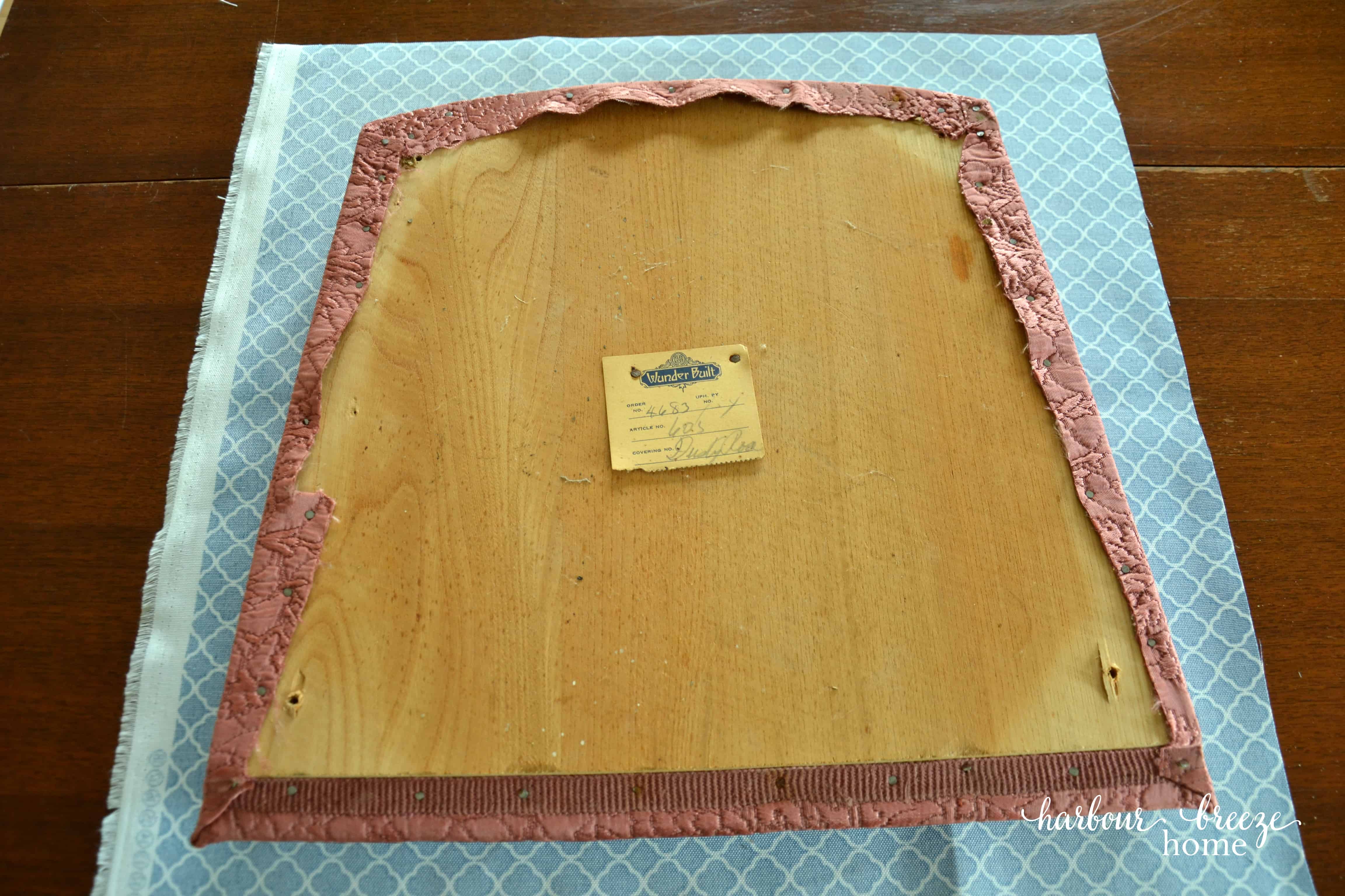 A chair cushion lying face down on the new fabric that will cover it.