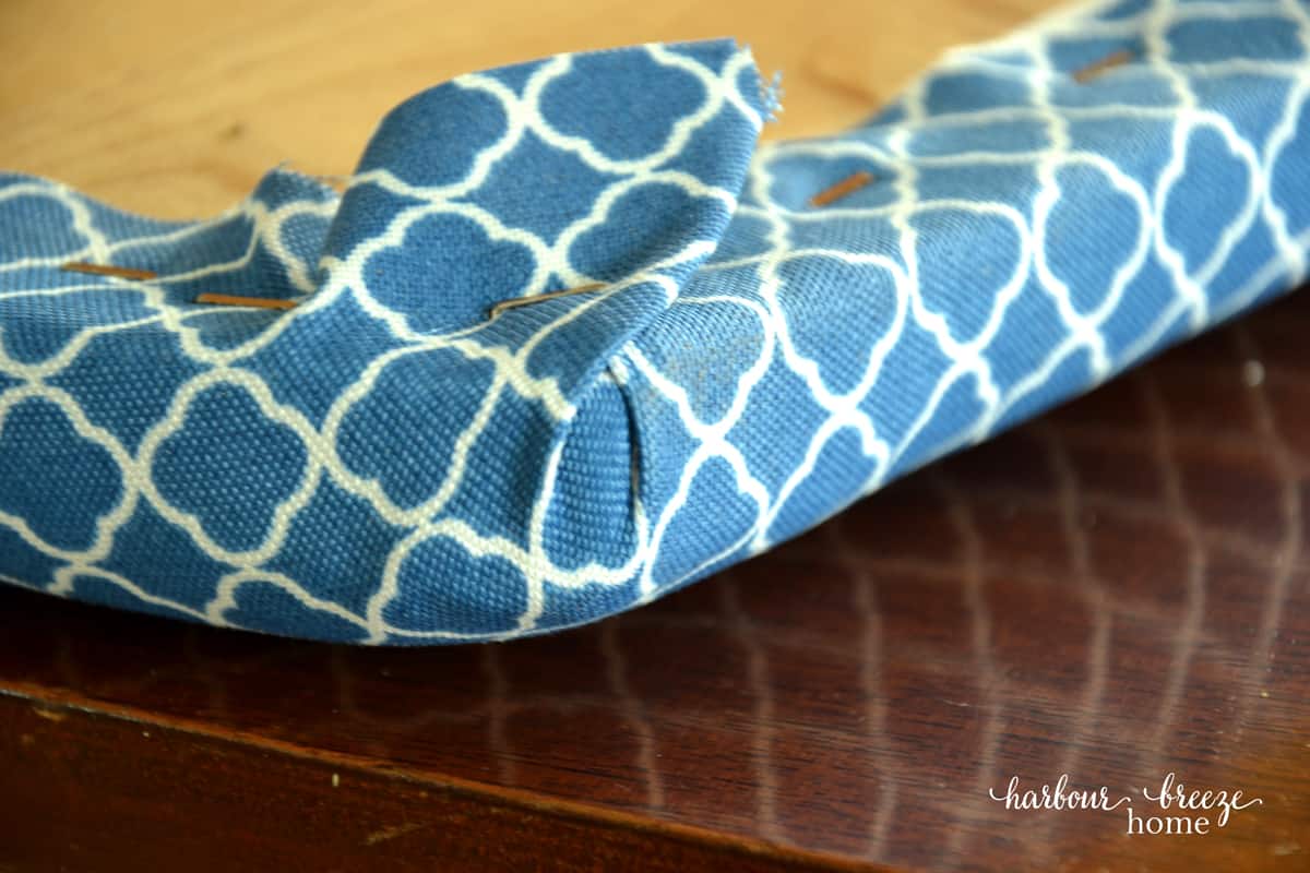 Close up of the corner of a dining chair cushion with a new fabric stapled on.