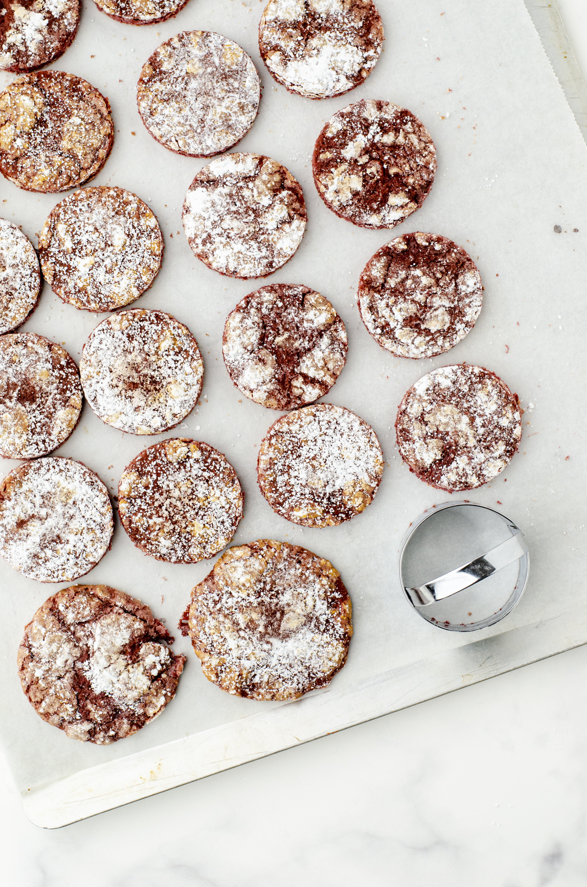 Red Velvet Cookies on a cookie sheet with most of them cut with a 3 inch cookie cutter.