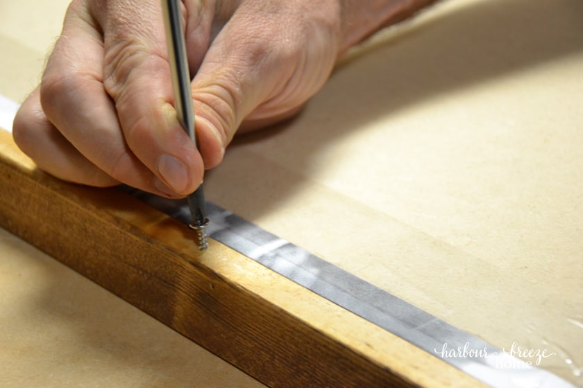 close up of a screw being placed in the side of a frame
