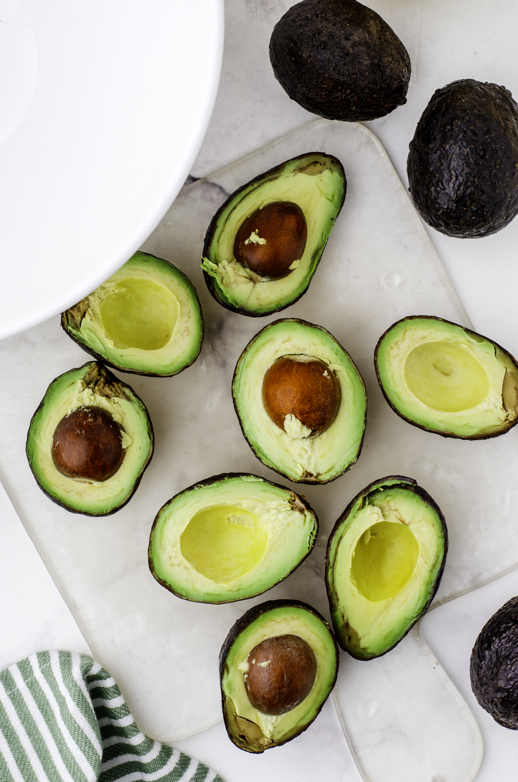Avocados cut in half and sitting on a cutting board.