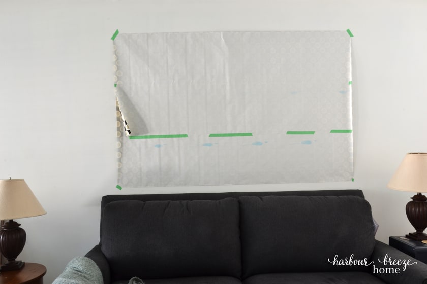 The gallery wall template paper taped above the wall above a couch