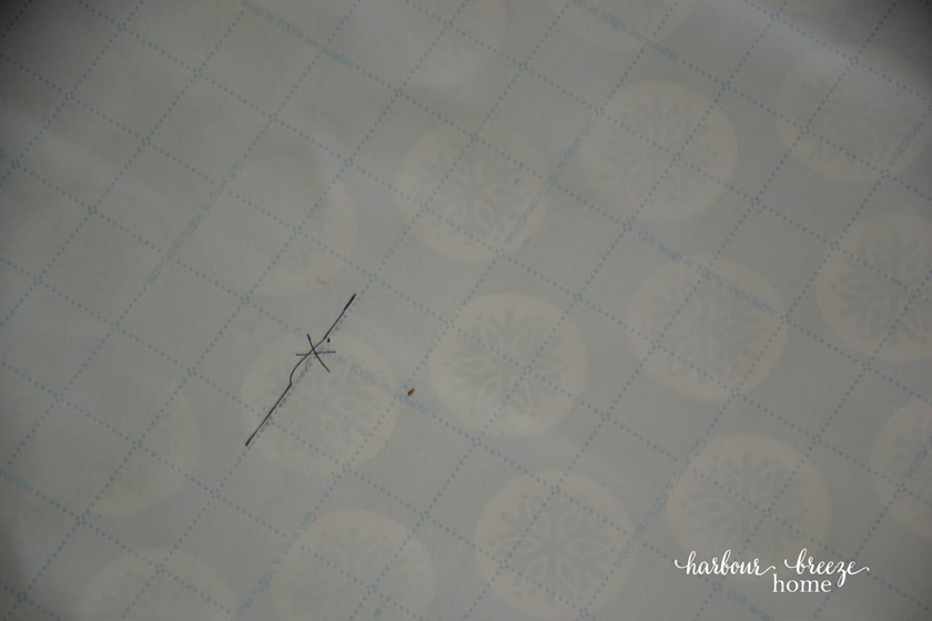 an "x" marked on the gallery wall template where a nail needs to go for proper picture placement