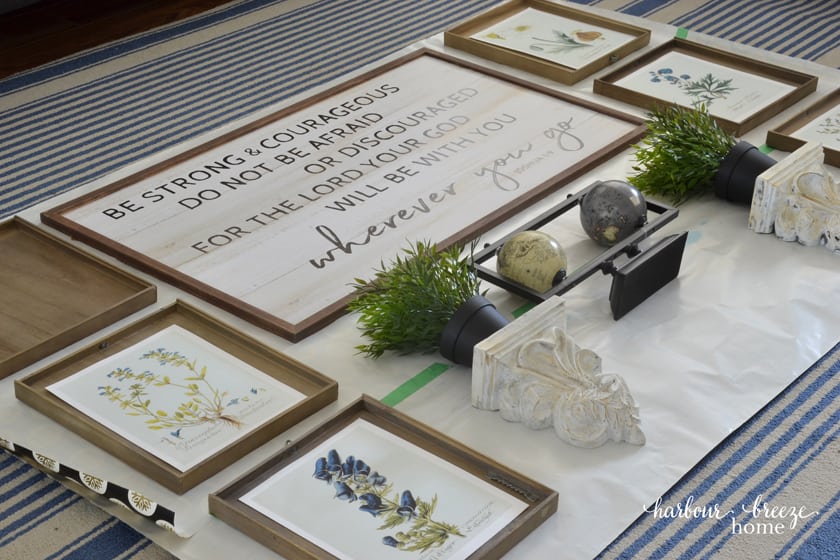 Wall decor items laid out on the gallery wall template paper on the floor in an arrangement.