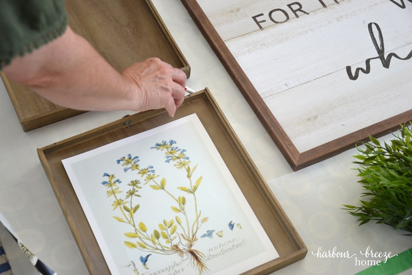 a lady marking the top of a picture on a gallery wall template with a pen