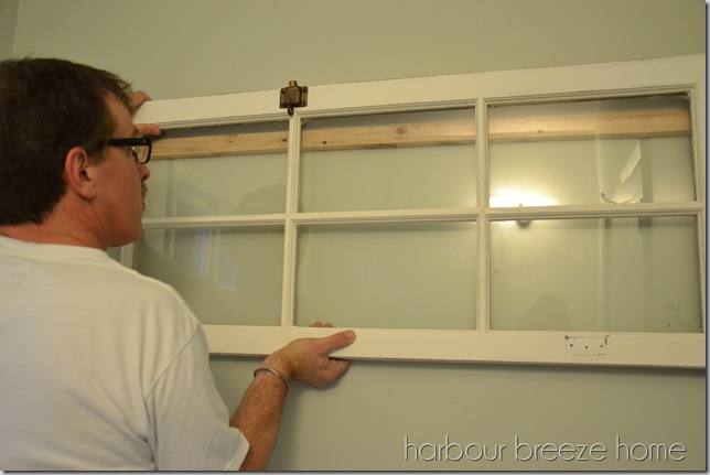 a large window being hung on a wall using a french cleat