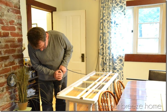 attaching the top of a french cleat to a large old window using a drill as a screwdriver