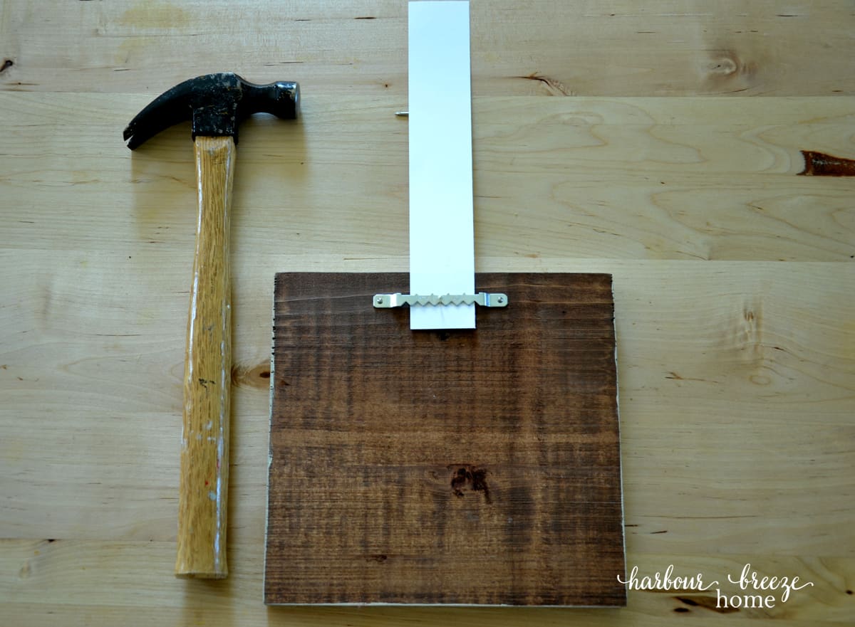 a frame with sawtooth hanger with a strip of paper with a thumbtack in it where the nail will need to go (how to hang a picture on the wall)