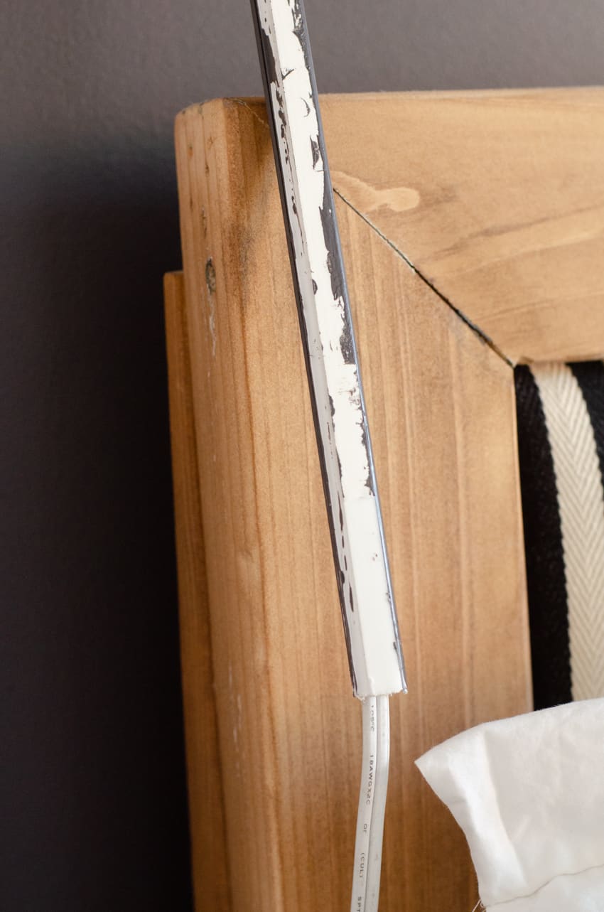A wall lamp cord cover wrapped around the wall lamp cord with the adhesive back ready to stick to the wall.