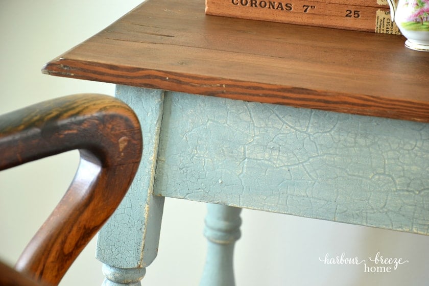 a wood stained table top with blue crackle finish on the legs and apron