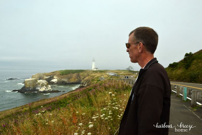 man looking out across the ocean with a lighthouse in the background