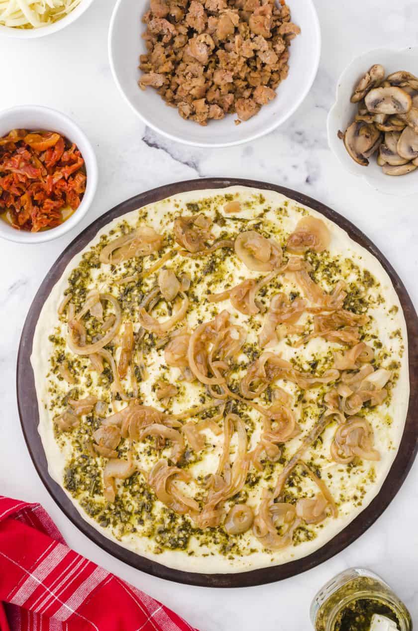 carmalized onions layered over pesto sauce on a pizza crust