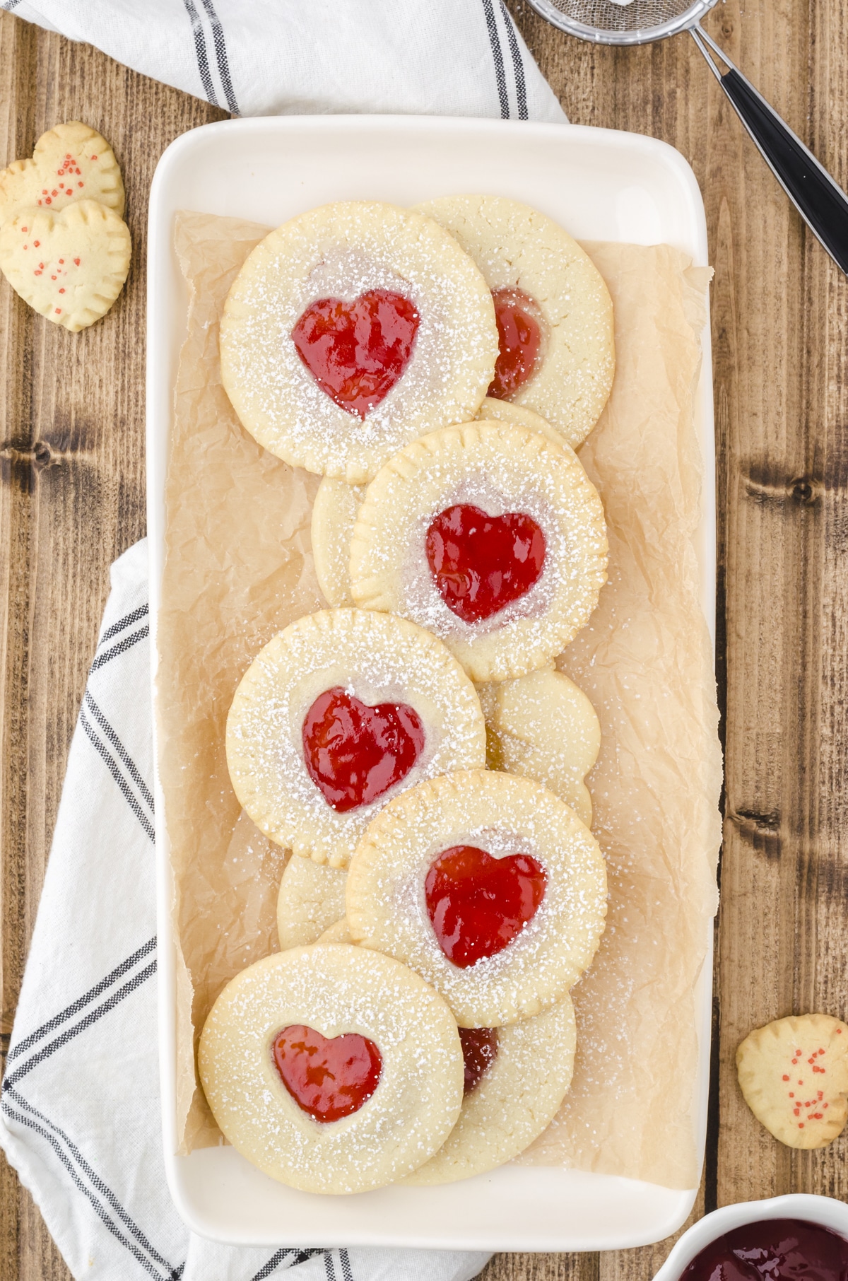 Jam Sandwich Cookies made with premade sugar cookie dough on a platter with red jam in heart cut outs.