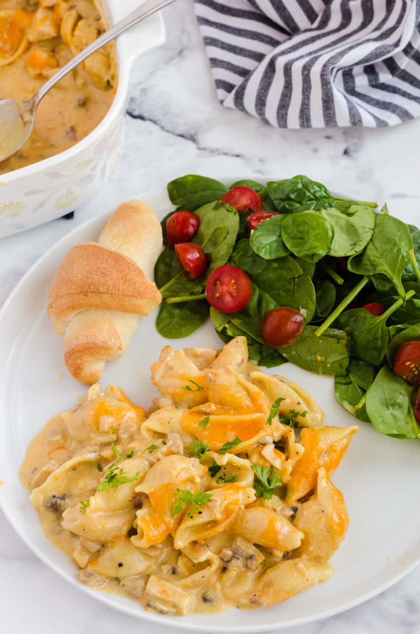 leftover turkey casserole recipe served on a plate with a side salad and dinner bun