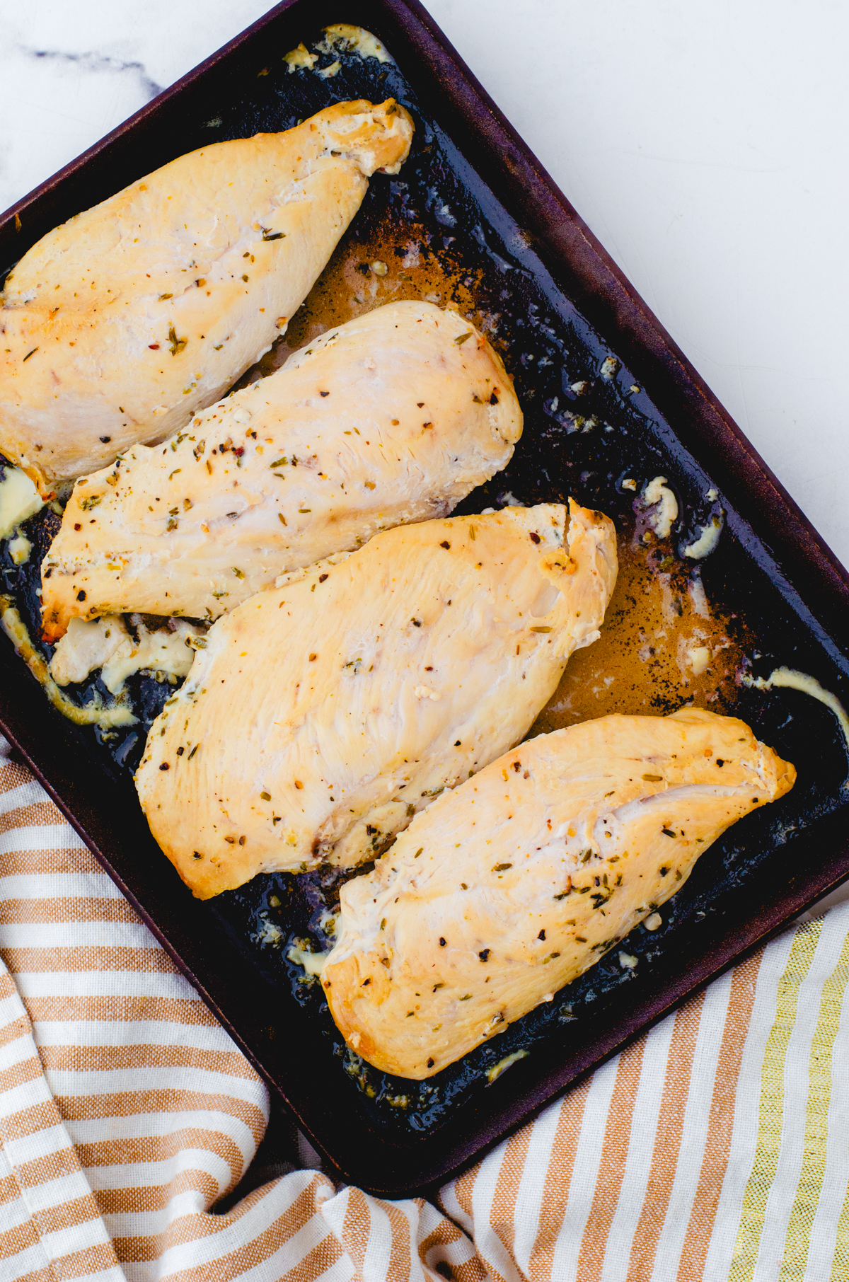 4 chicken breasts that have been marinaded in lemon chicken marinade baked in a stoneware baking pan.