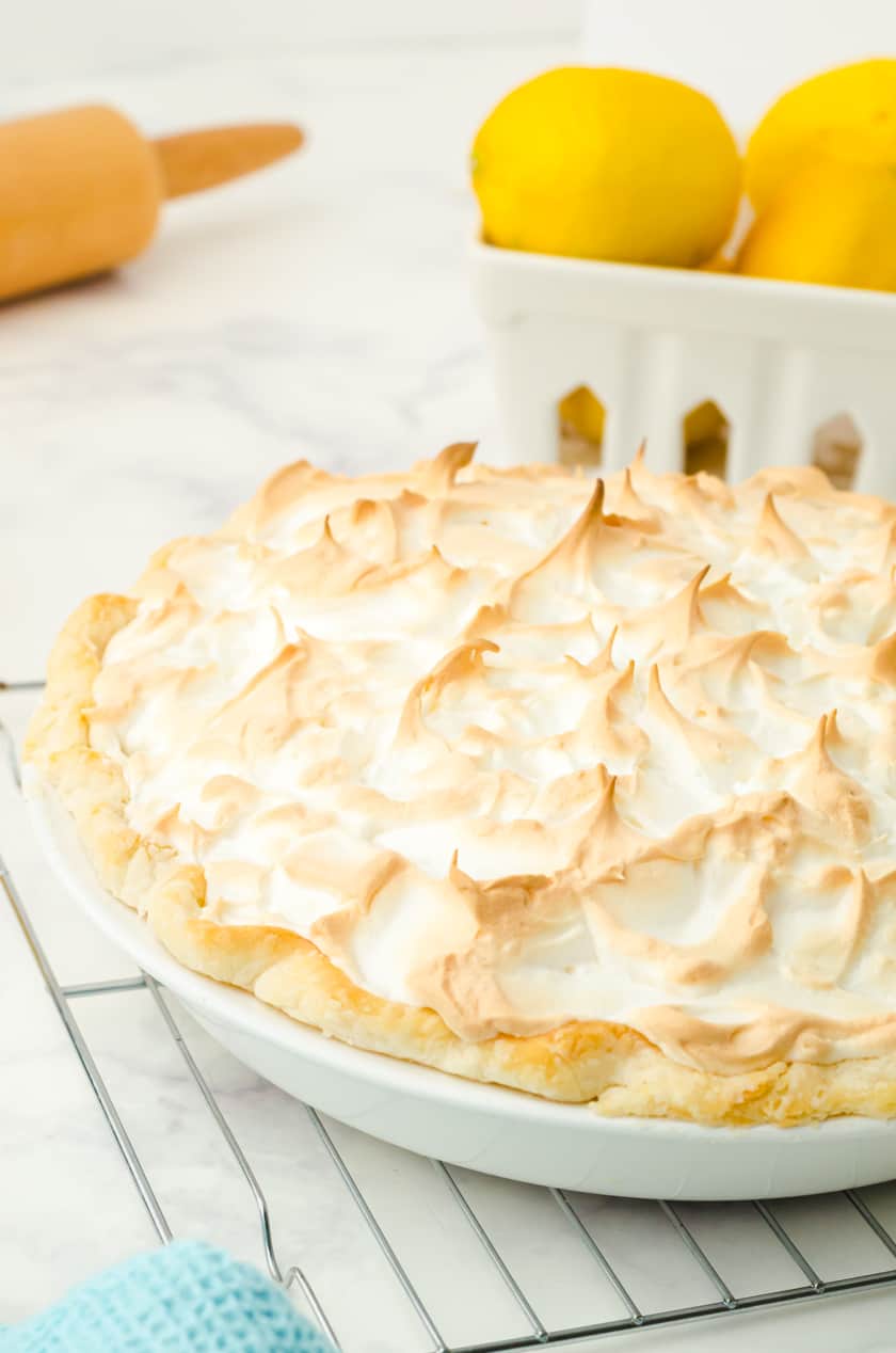 A lemon meringue pie cooling on a cooling rack.