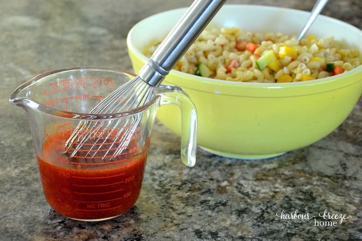 pasta salad ketchup dressing in a measuring cup with a whisk