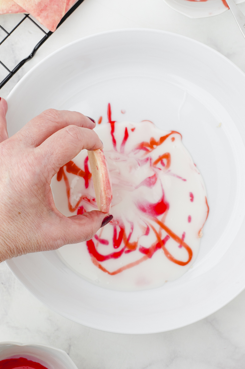 a woman pulling a cookie up and out of the icing