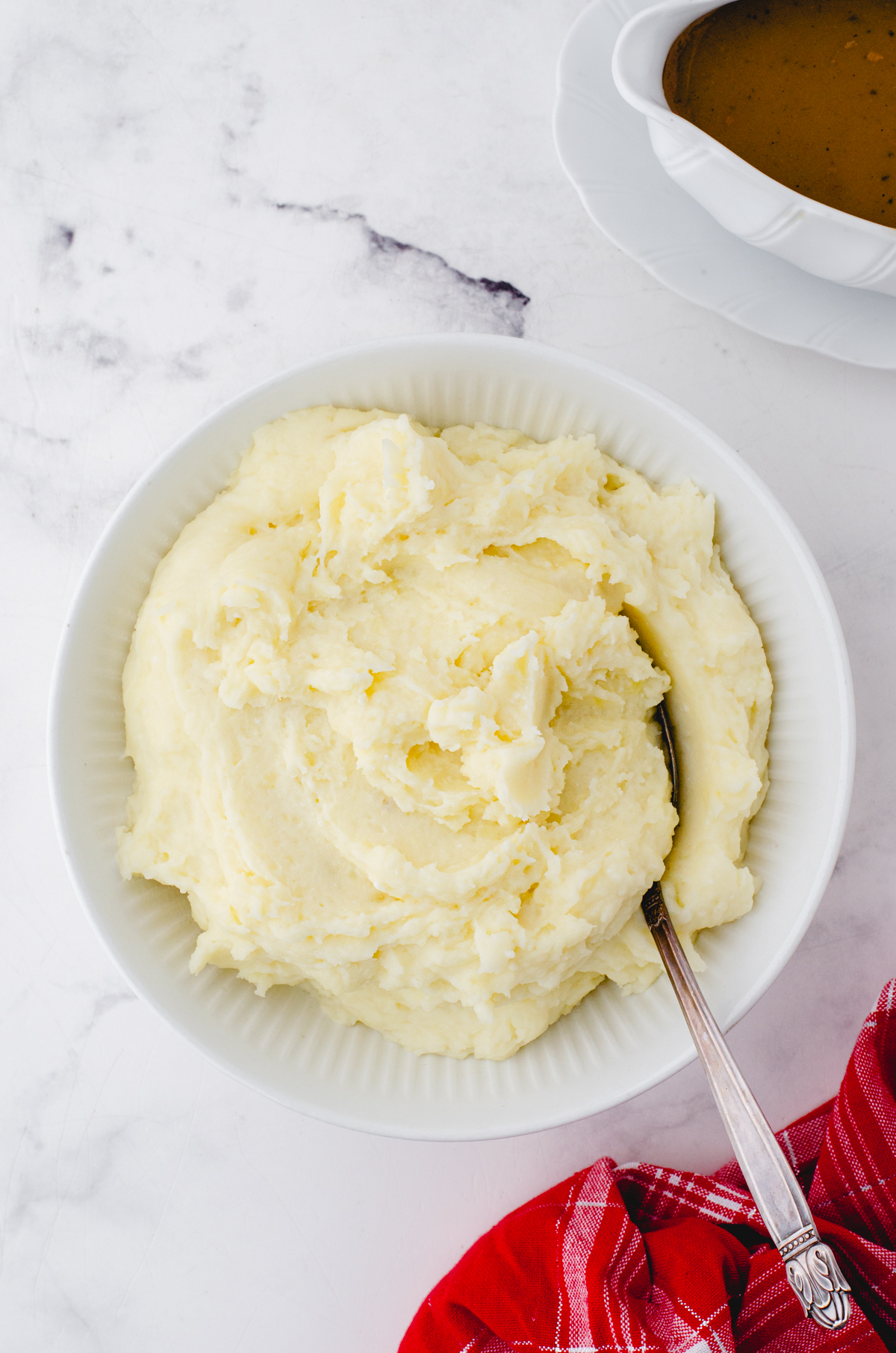 Whipped potatoes in a serving bowl with gravy beside.