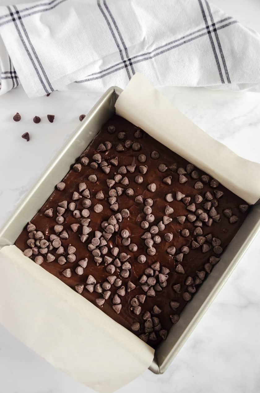 Black bean brownie batter poured into a parchment lined baking pan.