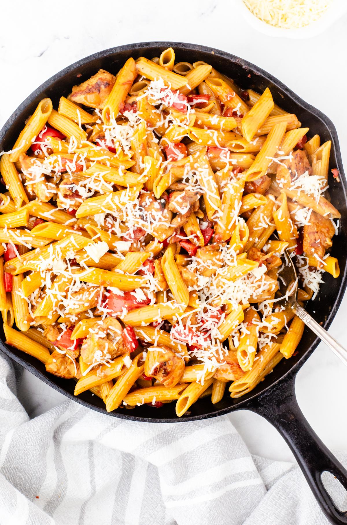 Cajun chicken pasta in a skillet with cheese sprinkled over the top.