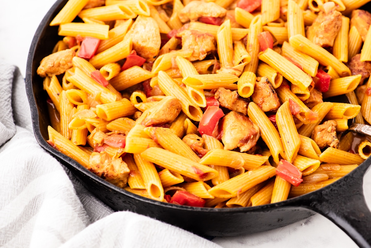 A cast iron skillet with one pot chicken pasta in it.