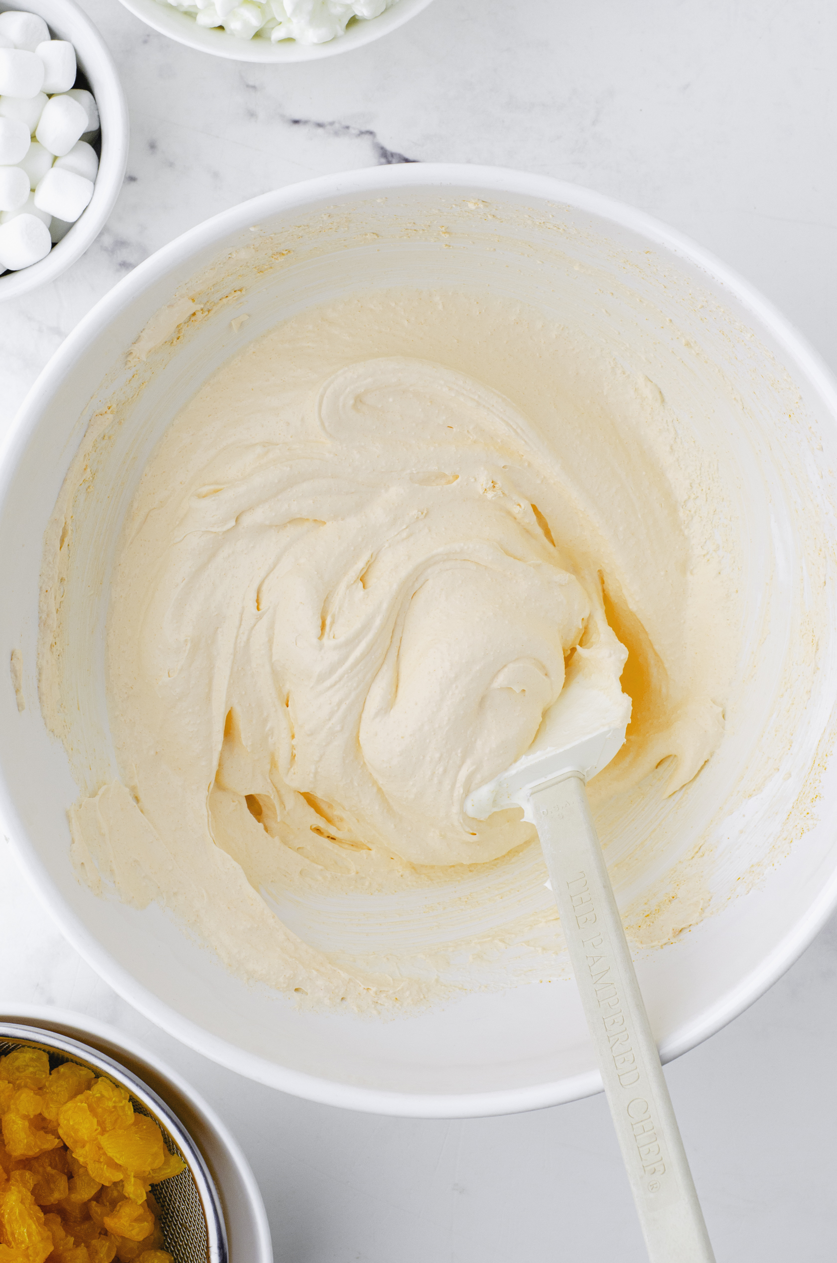 Cool whip and orange jello stirred together in a large mixing bowl.