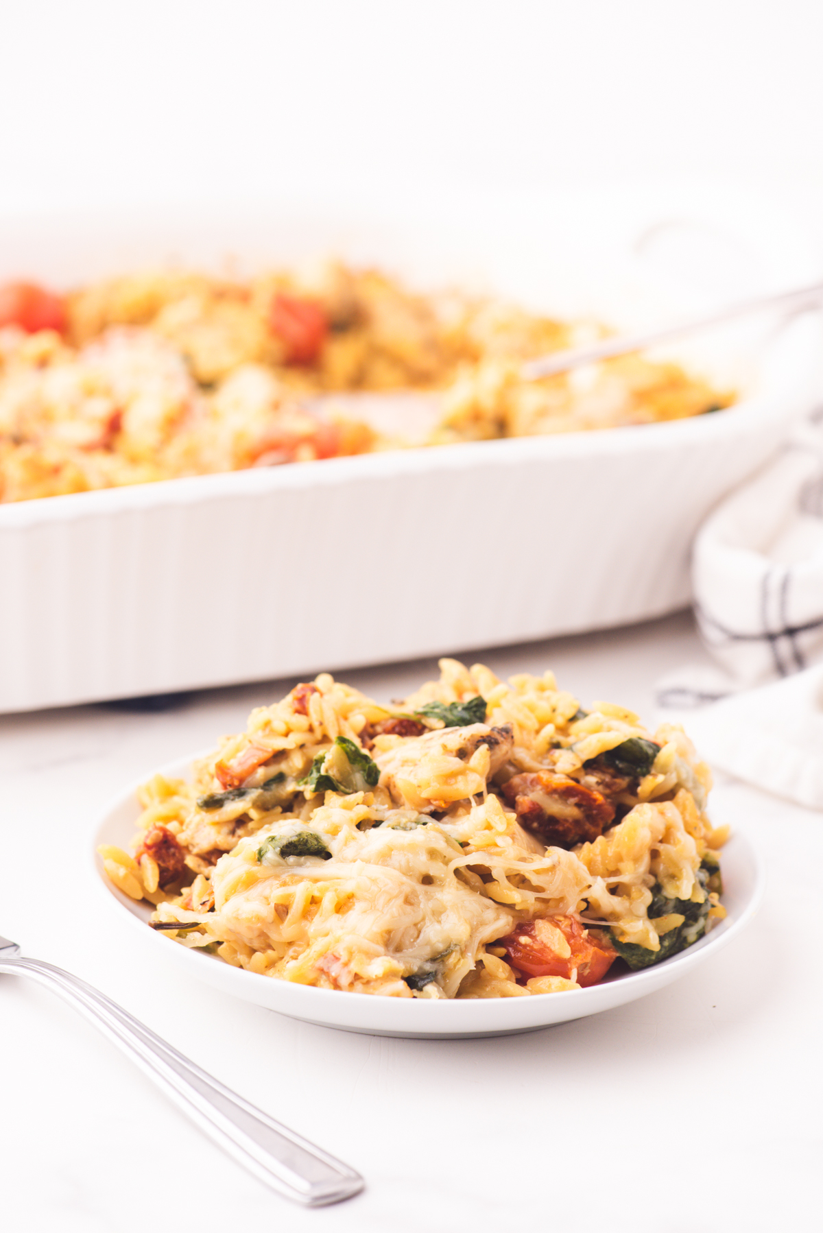 A plate with a serving of chicken orzo casserole on it.