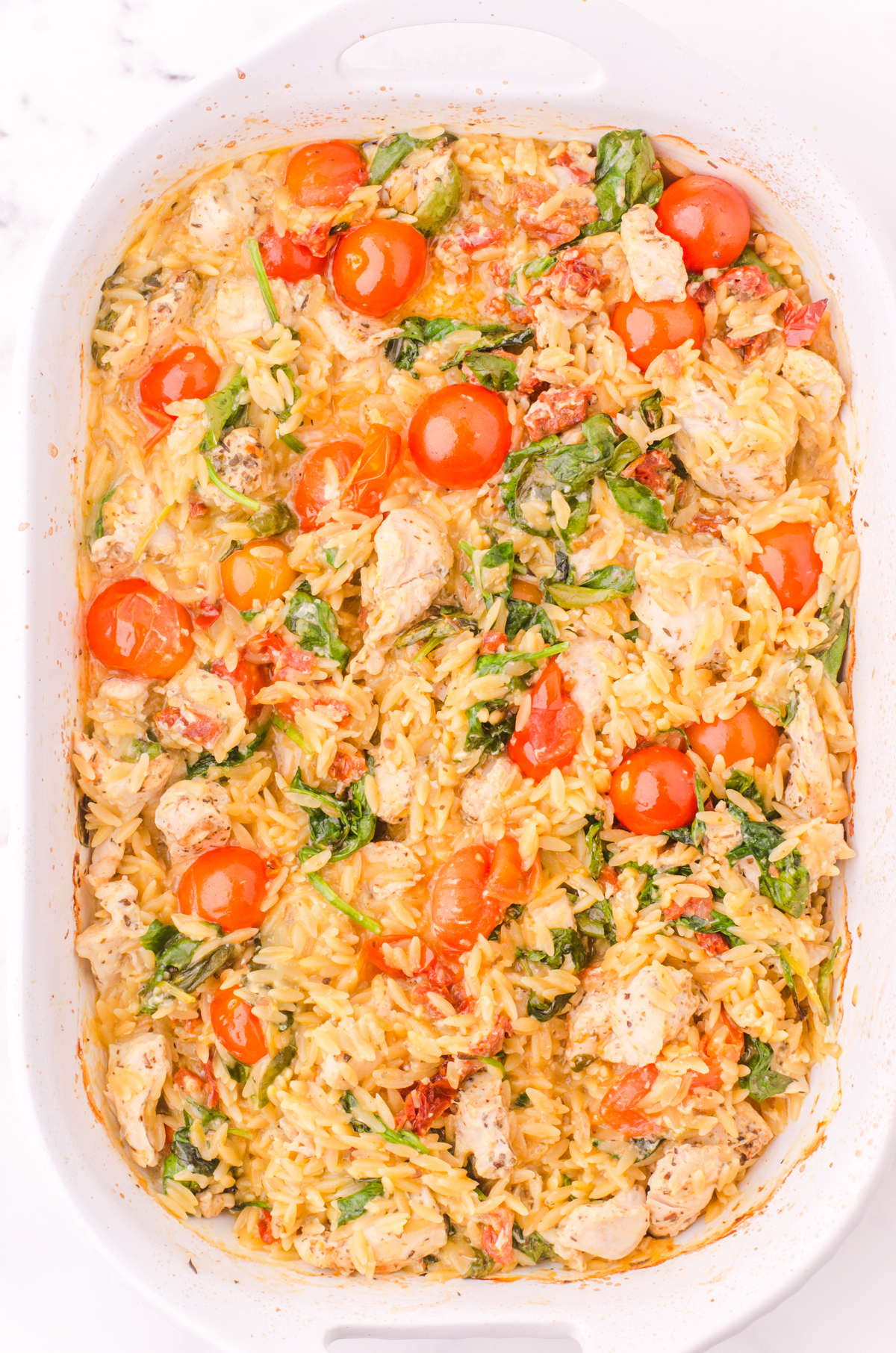 Baked chicken orzo casserole before parmesan cheese has been added.