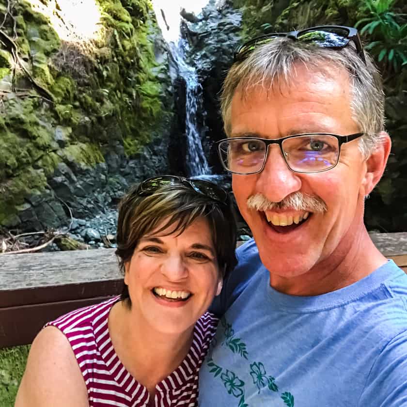 A couple standing in front of a waterfall on Vancouver Island, BC Canada.