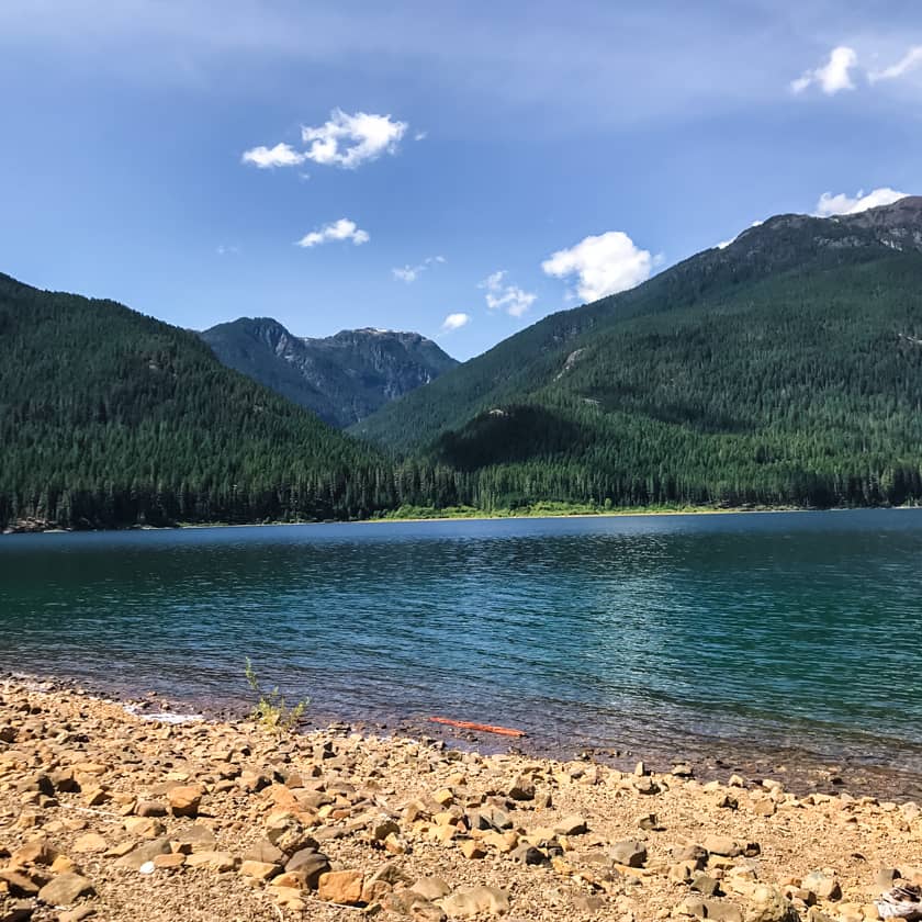 The clear blue-green water of Buttle Lake framed by a mountain range.