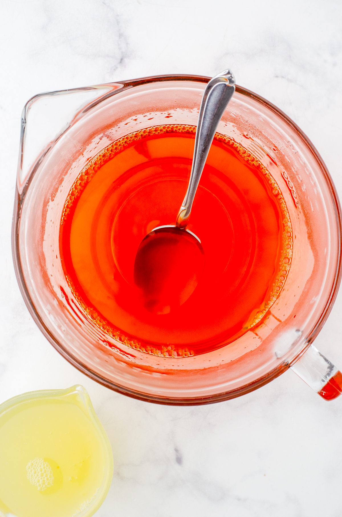 Jello powder being mixed with boiling water with reserved peach juice beside it.