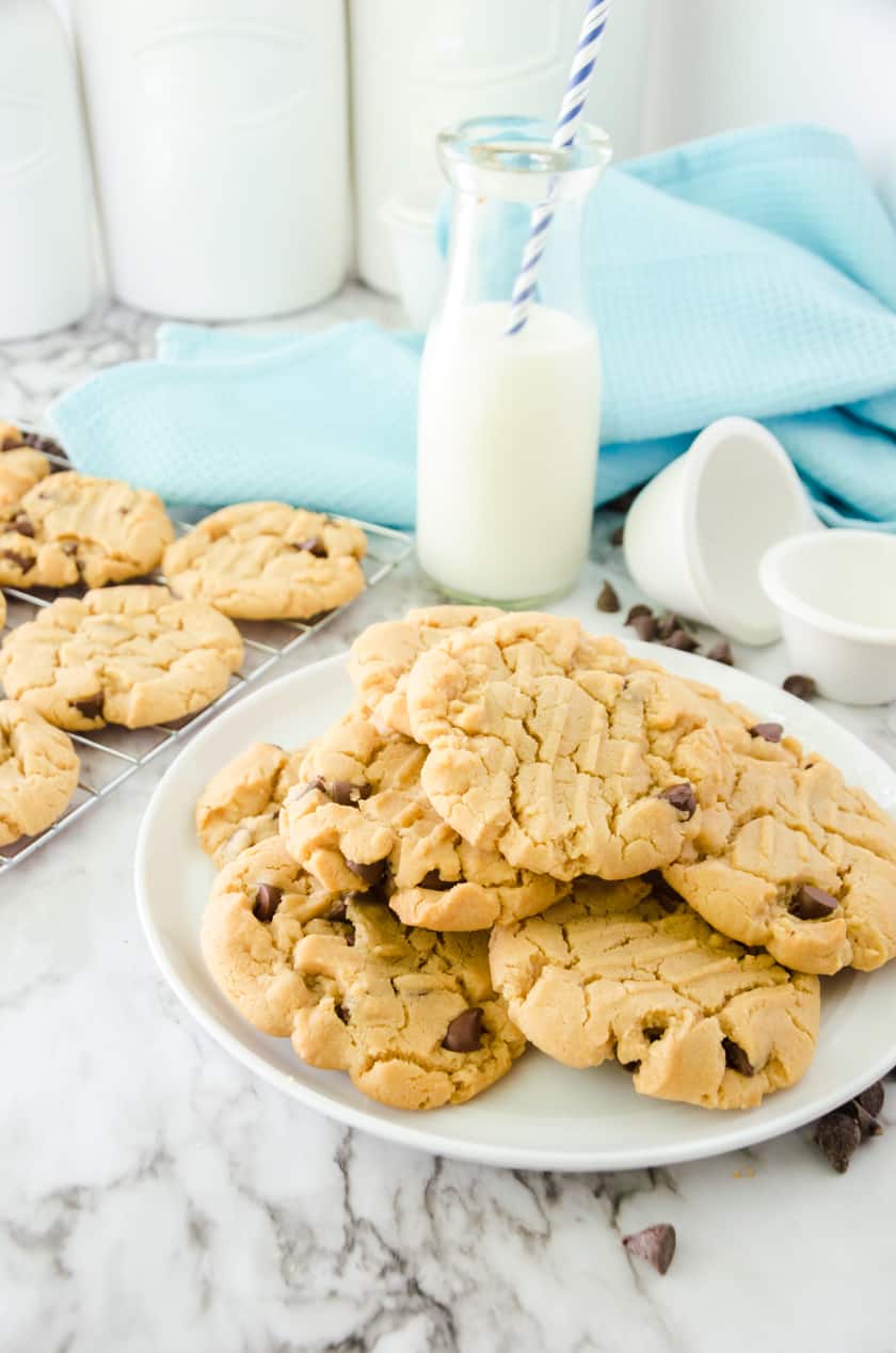 a plate of peanut butter chocolate chip cookies with a glass of milk behind it