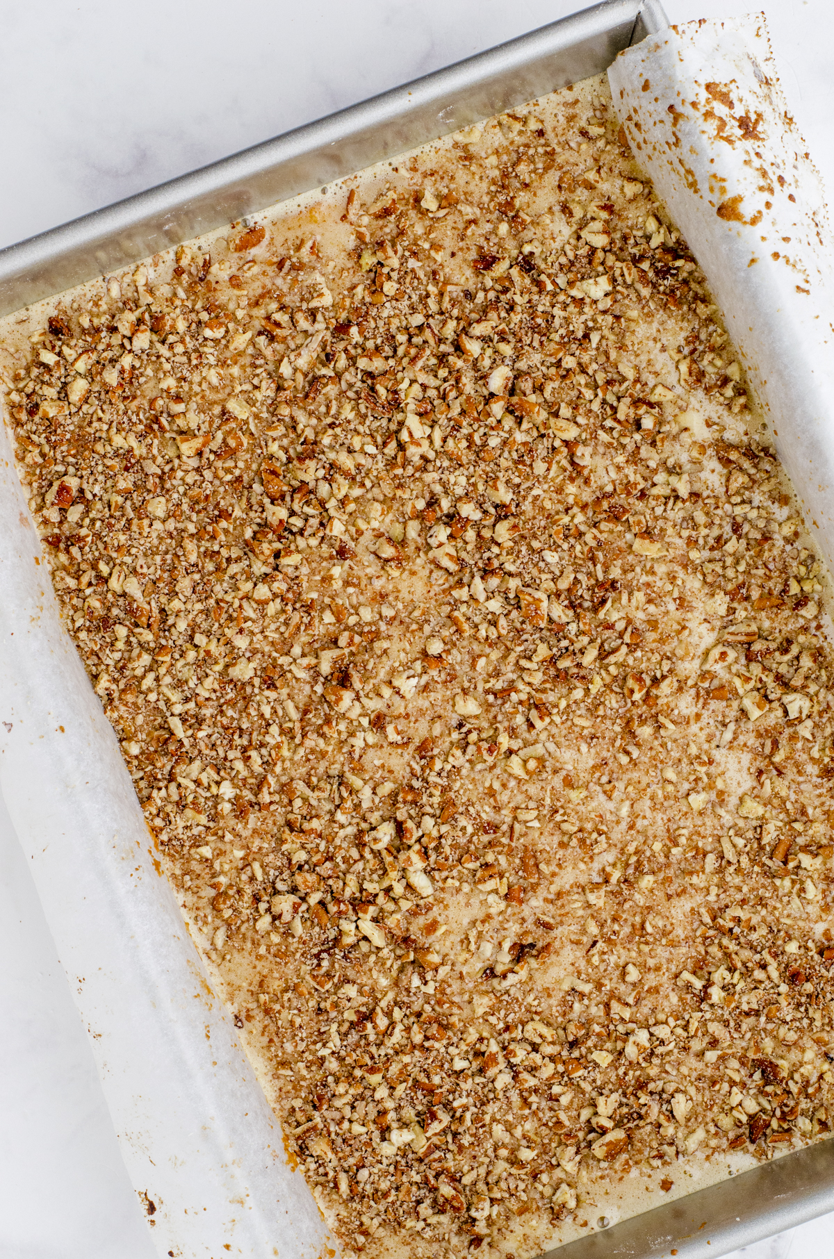 Chopped pecans sprinkled on the top of pecan pie bar filling.