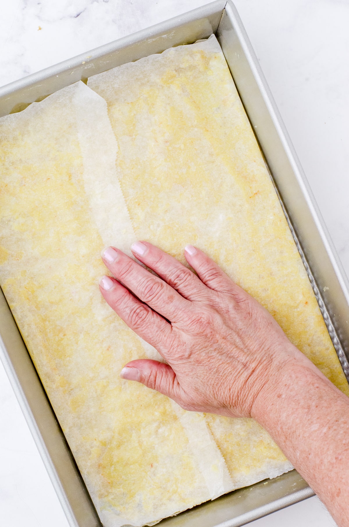 pressing the pecan pie bar crust into the bottom of a baking pan