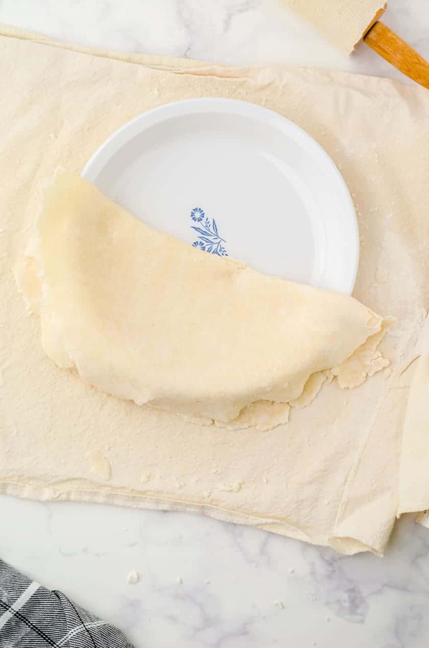 Pie crust being put in a pie pan.