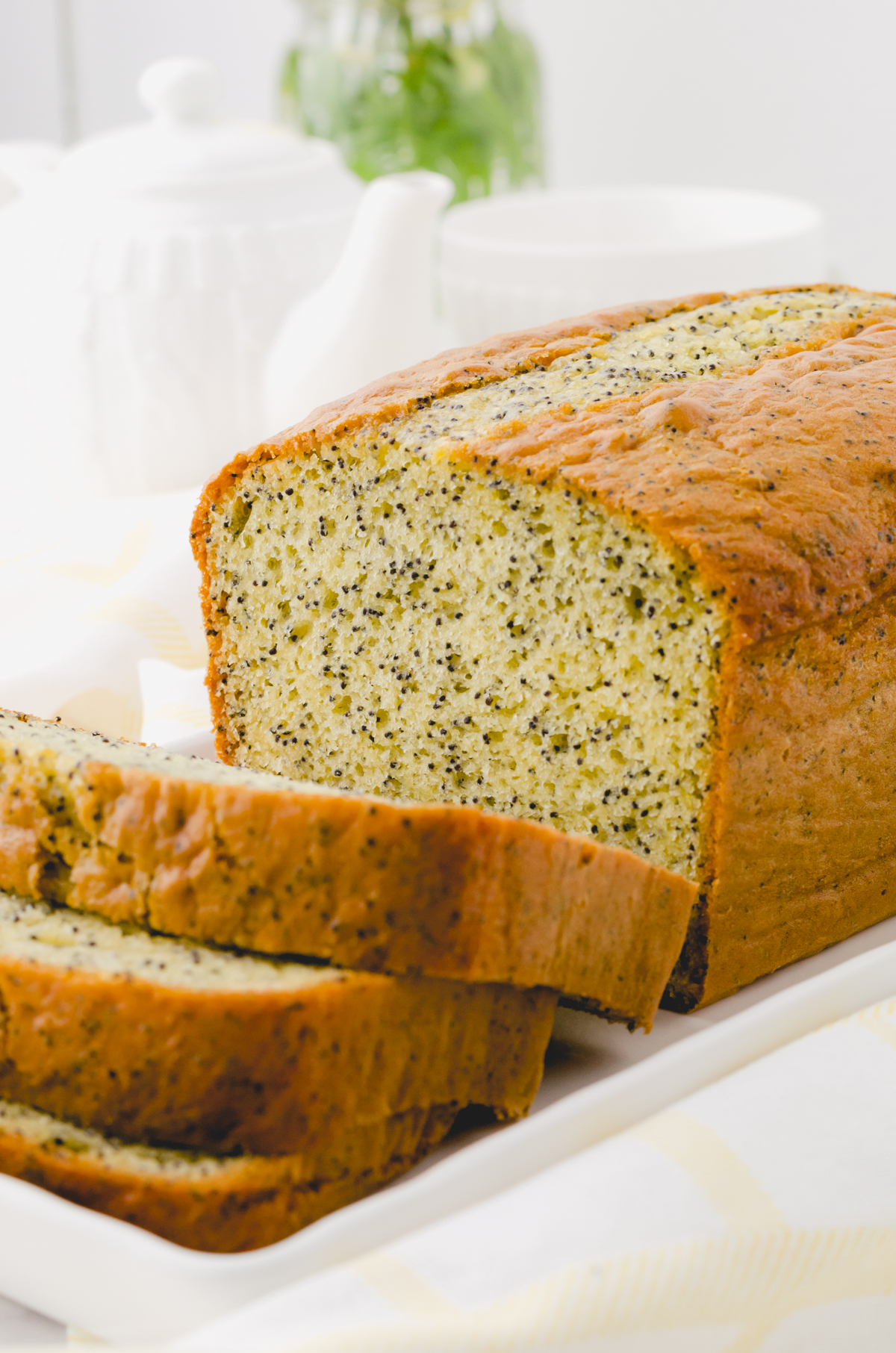 Sliced poppyseed bread on a white platter.