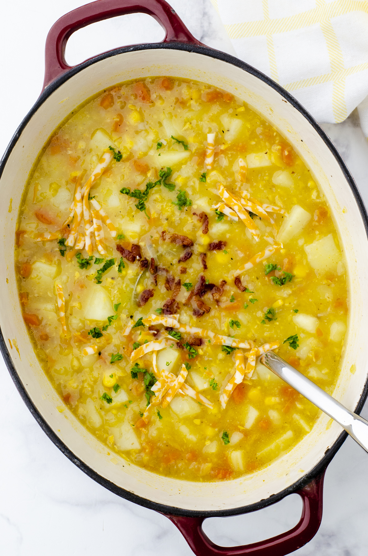 A pot of easy potato soup with chunky potatoes, corn, bacon bits, and shredded cheese.
