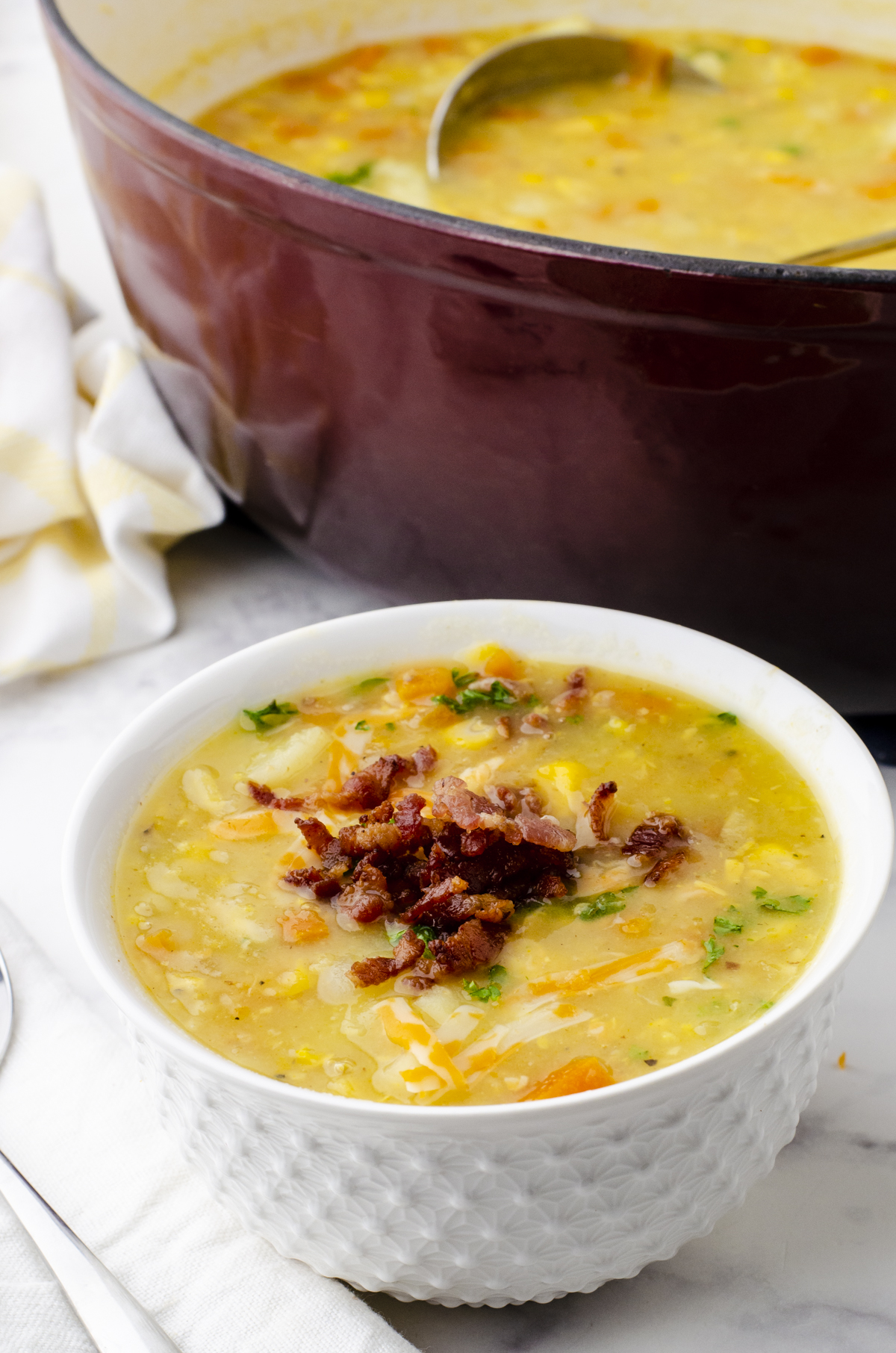 A bowl of creamy potato soup with bacon bits and cheese.