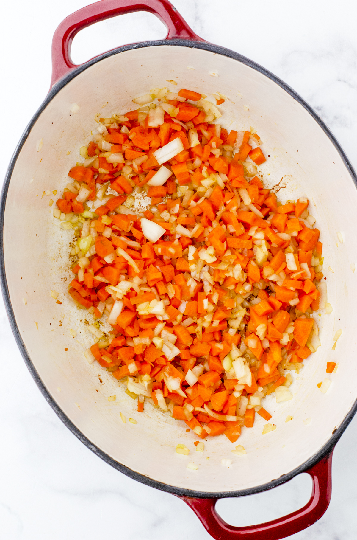 Diced carrots and onions in the bottom of a cast iron dutch oven.