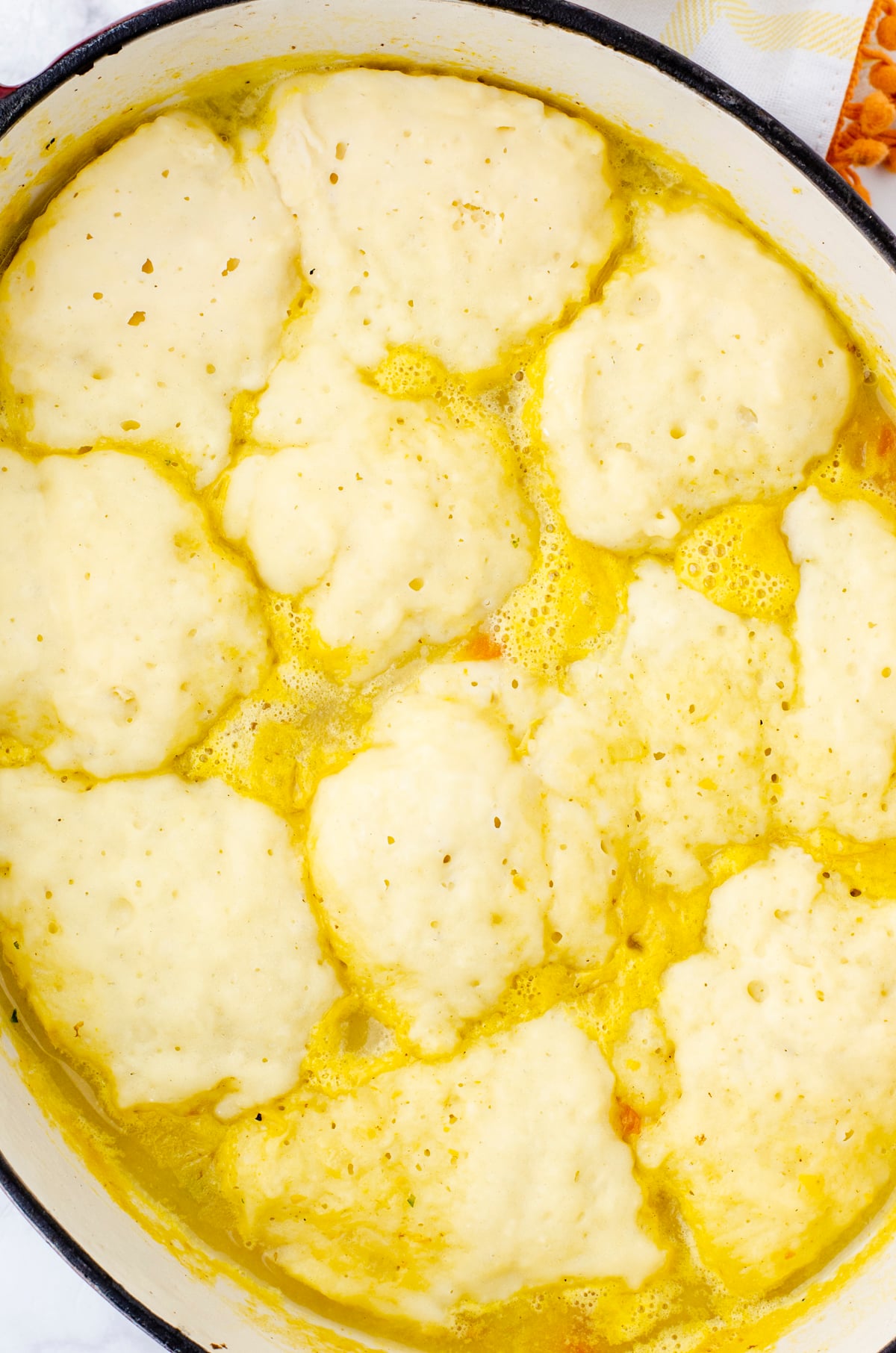 Dumpling recipe on top of a pot of potato soup.