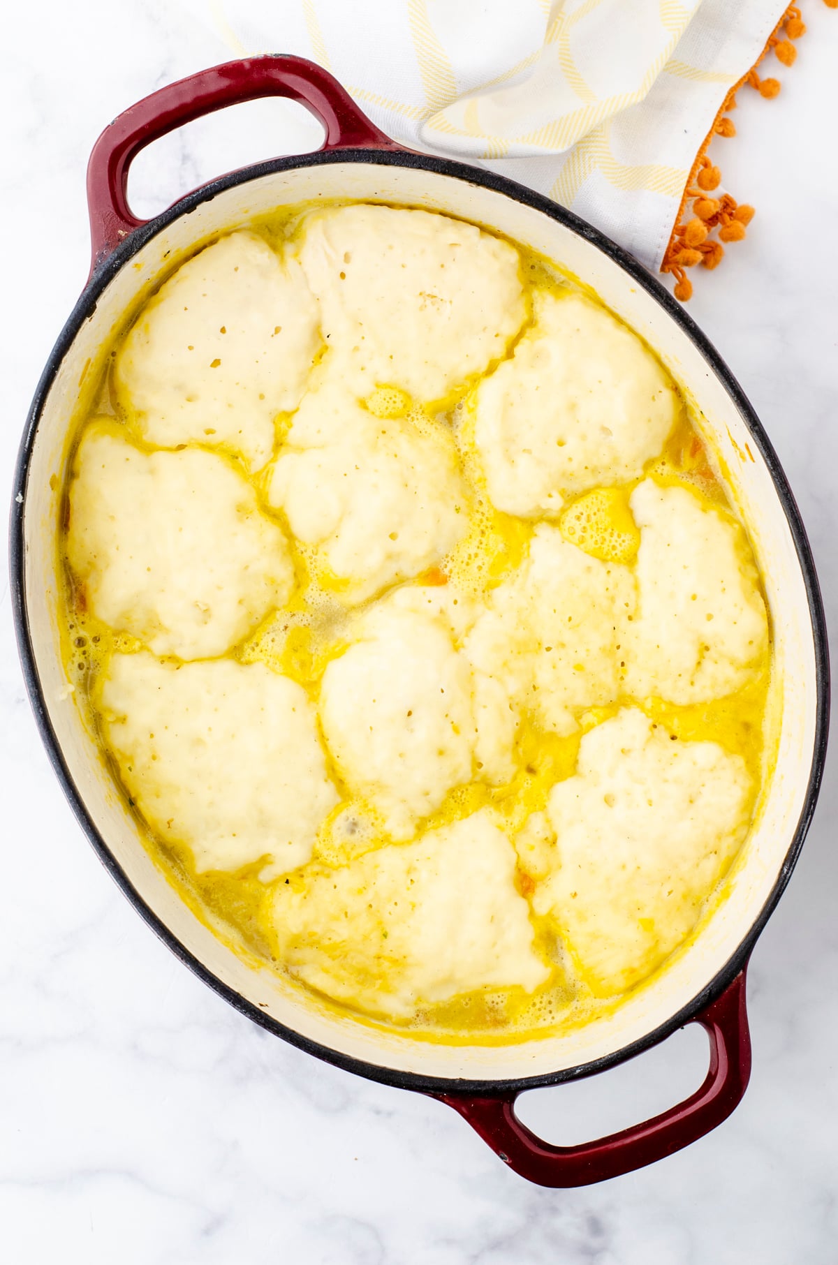 A pot of potato soup with cooked dropped dumplings on the top.