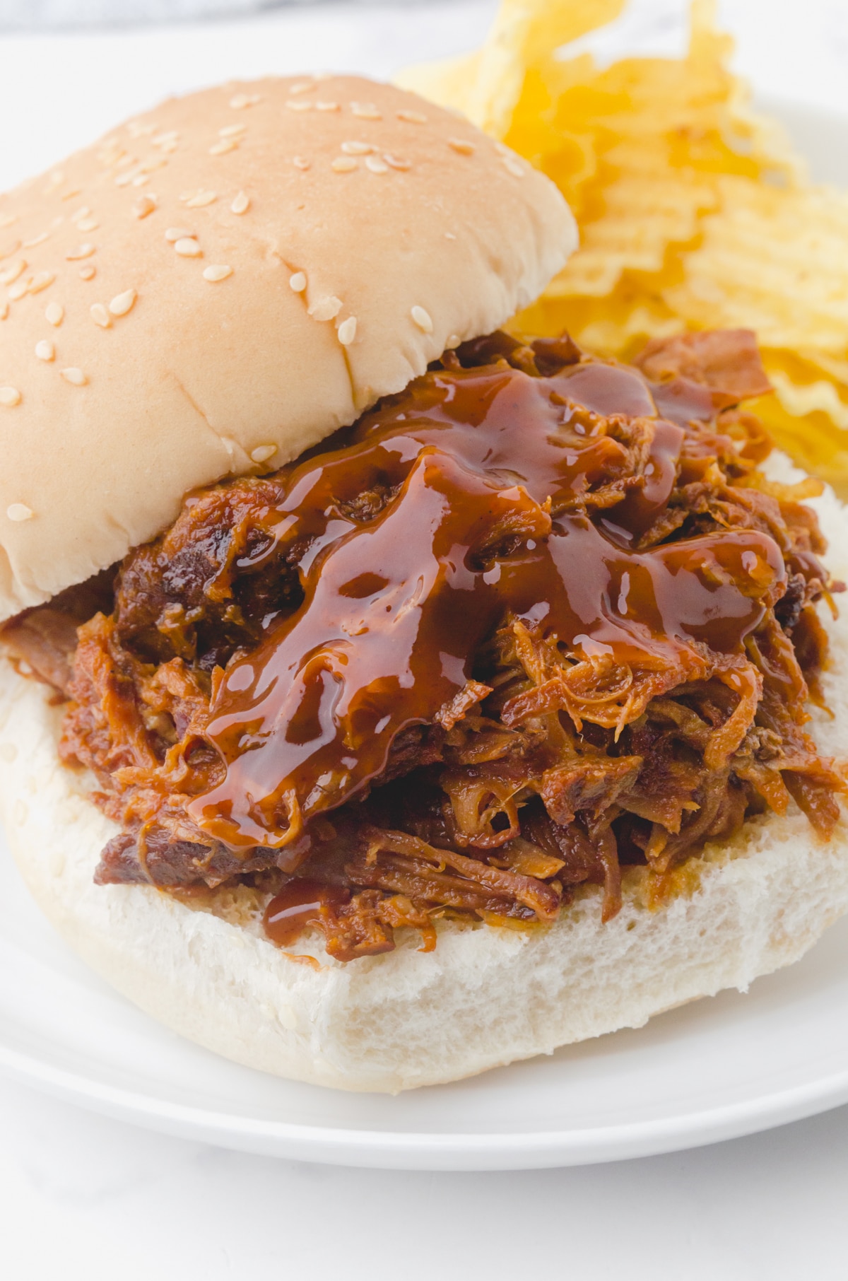 Best Ever Crock pot pulled pork piled on a bun and topped with a drizzle of bbq sauce.